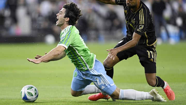 May 14, 2025; Los Angeles, California, USA;  Seattle Sounders midfielder Paul Rothrock (14) gets tripped up by Los Angeles FC midfielder Timothy Tillman (11) during the first half at BMO Stadium. Mandatory Credit: Alex Gallardo-Imagn Images