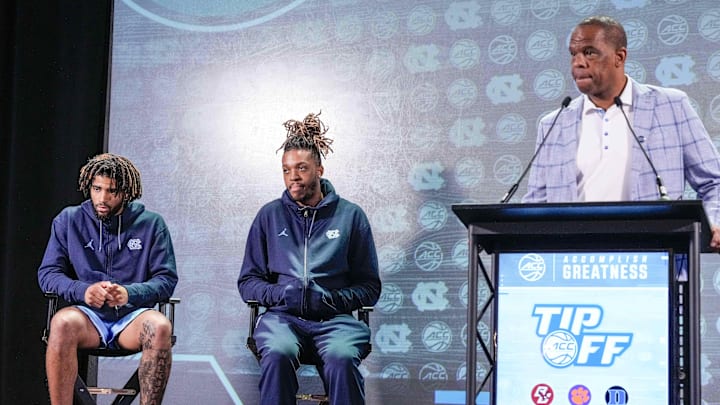 Oct 25, 2023; Charlotte, NC, USA;  North Carolina players RJ Davis and Armando Bacot listen as coach Hubert Davis speaks to the media during the ACC Tipoff at Hilton Charlotte Uptown. Mandatory Credit: Jim Dedmon-Imagn Images