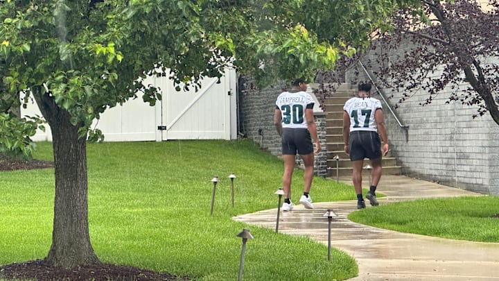 Eagles linebackers Jihaad Campbell and Nakobe Dean work their way through the rain as the Eagles' OTA practice began. The two injured players were on their way to likely receive rehab, returning after the OTA practice was about half over on May 28, 2025.