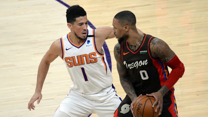 Feb 22, 2021; Phoenix, Arizona, USA; Phoenix Suns guard Devin Booker (1) guards Portland Trail Blazers guard Damian Lillard (0) during the first half at Phoenix Suns Arena. Mandatory Credit: Joe Camporeale-Imagn Images