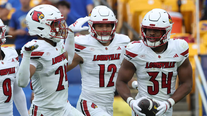 Sep 27, 2025; Pittsburgh, Pennsylvania, USA;  Louisville Cardinals defensive back Corey Gordon (24) and linebacker Kalib Perry (12) celebrate an interception by linebacker TJ Quinn (34) against the Pittsburgh Panthers during the fourth quarter at Acrisure Stadium. Mandatory Credit: Charles LeClaire-Imagn Images