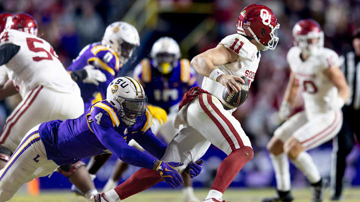 Nov 30, 2024; Baton Rouge, Louisiana, USA; Oklahoma Sooners quarterback Jackson Arnold (11) evades the sack attempt of LSU Tigers defensive end Bradyn Swinson (4) during the fourth quarter at Tiger Stadium. Mandatory Credit: Stephen Lew-Imagn Images Nov 30, 2024; Baton Rouge, Louisiana, USA; Oklahoma Sooners quarterback Jackson Arnold (11) evades the sack attempt of LSU Tigers defensive end Bradyn Swinson (4) during the fourth quarter at Tiger Stadium. Mandatory Credit: Stephen Lew-Imagn Images