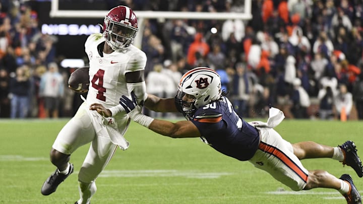 Nov 25, 2023; Auburn, Alabama, USA;  Auburn Tigers linebacker Larry Nixon III (30) shoves Alabama Crimson Tide quarterback Jalen Milroe (4) toward the sidelines at Jordan-Hare Stadium. Alabama won 27-24. Mandatory Credit: Gary Cosby Jr.-Imagn Images