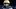 High school quarterback Carper stands on the field in a black football uniform and gold helmet, looking toward the sideline b High school quarterback Carper stands on the field in a black football uniform and gold helmet, looking toward the sideline b