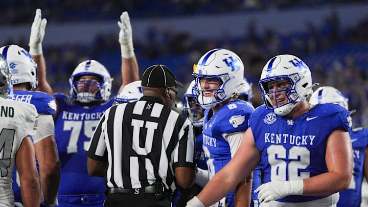 As Kentucky Wildcats offensive lineman Joshua Braun (75) signals touchdown, Kentucky Wildcats quarterback Cutter Boley (8) and Kentucky Wildcats offensive lineman Jager Burton (62) smile as the Cats roll past Eastern Michigan 48-23 at Kroger Field in Lexington, Kentucky Saturday, Sept. 13, 2025.
