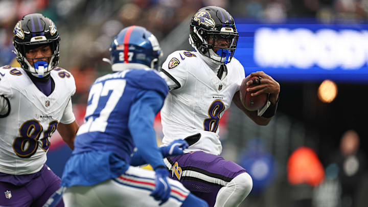 Dec 15, 2024; East Rutherford, New Jersey, USA; Baltimore Ravens quarterback Lamar Jackson (8) carries the ball as New York Giants safety Jason Pinnock (27) pursues during the first half at MetLife Stadium. Mandatory Credit: Vincent Carchietta-Imagn Images