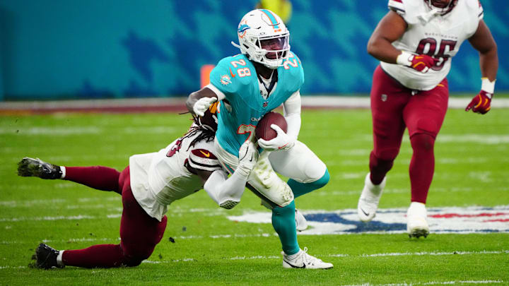 Miami Dolphins running back De'Von Achane (28) carries the ball defended by Washington Commanders linebacker Jordan Magee (58) in the second quarter during the 2025 NFL Madrid Game at Santiago Bernabeu Stadium. 