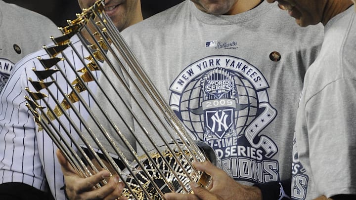 Nov 4, 2009; Bronx, NY, USA; FILE PHOTO; New York Yankees shortstop Derek Jeter (center), Jorge Posada (left), and Mariano Rivera (right) look at the championship trophy after beating the Phillies to win their 27th championship. The Yankees beat the Philadelphia Phillies 7-3 in game 6 of the 2009 World Series at Yankee Stadium.  Mandatory Credit: Robert Hanashiro-Imagn Images