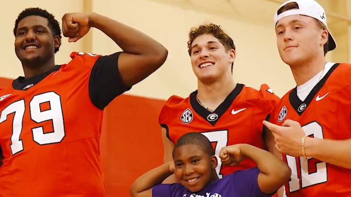 Georgia Bulldog football players pose for a picture with a Boys and Girls Club member