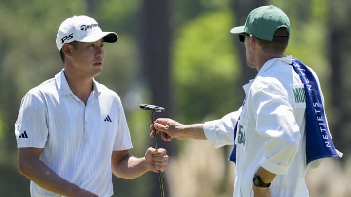Collin Morikawa hands his putter to caddie Mark Urbanek. Collin Morikawa hands his putter to caddie Mark Urbanek.