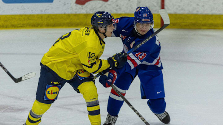 Aug 2, 2024; Plymouth, MI, USA; USA’s defenceman Lukas Fischer (13) battles for position with Sweden's forward Victor Eklund (18) during the first period of the 2024 World Junior Summer Showcase at USA Hockey Arena. Mandatory Credit: David Reginek-Imagn Images