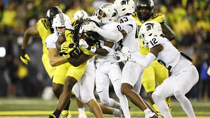 Oct 4, 2024; Eugene, Oregon, USA; Michigan State Spartans defensive back Charles Brantley (0), defensive back Malik Spencer (43), and defensive back Justin Denson Jr. (12) tackle Oregon Ducks running back Jordan James (20) during the first half at Autzen Stadium. Mandatory Credit: Troy Wayrynen-Imagn Images