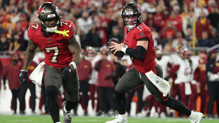 Tampa Bay Buccaneers quarterback Baker Mayfield (right) rolls out behind Bucky Irving during an NFL playoff game.