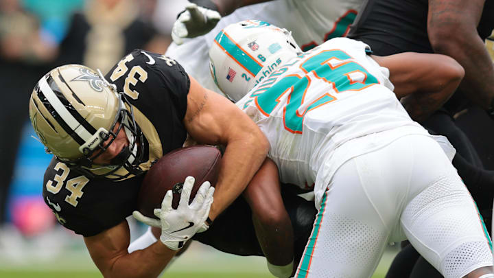 Nov 30, 2025; Miami Gardens, Florida, USA; New Orleans Saints running back Evan Hull (34) is tackled by. Miami Dolphins cornerback Rasul Douglas (26) during the second half at Hard Rock Stadium. Mandatory Credit: Sam Navarro-Imagn Images