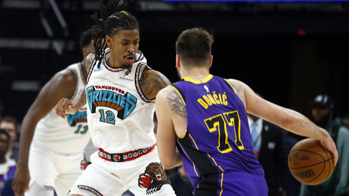 Mar 29, 2025; Memphis, Tennessee, USA; Memphis Grizzlies guard Ja Morant (12) defends as Los Angeles Lakers guard Luka Doncic (77) drives to the basket during the fourth quarter at FedExForum. Mandatory Credit: Petre Thomas-Imagn Images