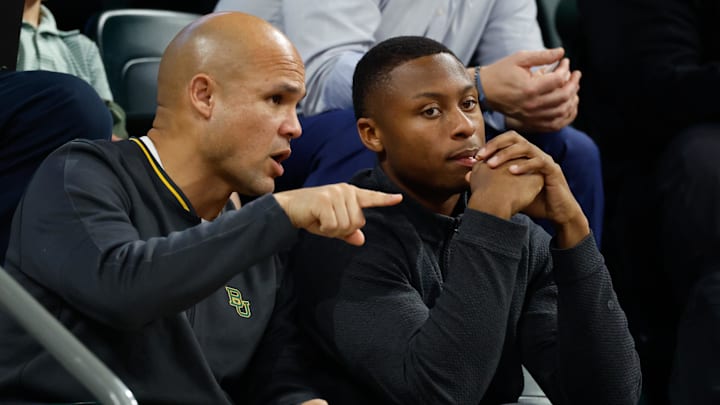 Jan 7, 2026; Waco, Texas, USA; DJ Lagway, a Florida quarterback currently in the transfer portal, sits with Baylor Bears football head coach Dave Aranda, left, during the first half of a game between the Baylor Bears and Iowa State Cyclones at Paul and Alejandra Foster Pavilion. Mandatory Credit: Chris Jones-Imagn Images Jan 7, 2026; Waco, Texas, USA; DJ Lagway, a Florida quarterback currently in the transfer portal, sits with Baylor Bears football head coach Dave Aranda, left, during the first half of a game between the Baylor Bears and Iowa State Cyclones at Paul and Alejandra Foster Pavilion. Mandatory Credit: Chris Jones-Imagn Images