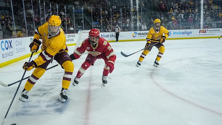Noah Beck (2) of the Arizona State Sun Devils moves the puck near the boards, followed by Jake Fisher (19) of the Denver Pioneers and teammate, Kyle Smolen (25) during game at Mullett Arena on Feb. 8, 2025, in Tempe.