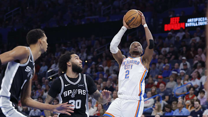 Dec 25, 2025; Oklahoma City, Oklahoma, USA; Oklahoma City Thunder guard Shai Gilgeous-Alexander (2) shoots beside San Antonio Spurs forward Julian Champagnie (30) during the second half at Paycom Center. Mandatory Credit: Alonzo Adams-Imagn Images