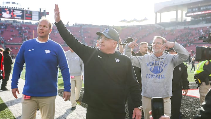 Kentucky Wildcats head coach Mark Stoops waves to the UK fans as special assistant Eddie Gran throws down Ls after the Wildcats beat Louisville 38-31 Saturday. Nov. 24, 2023