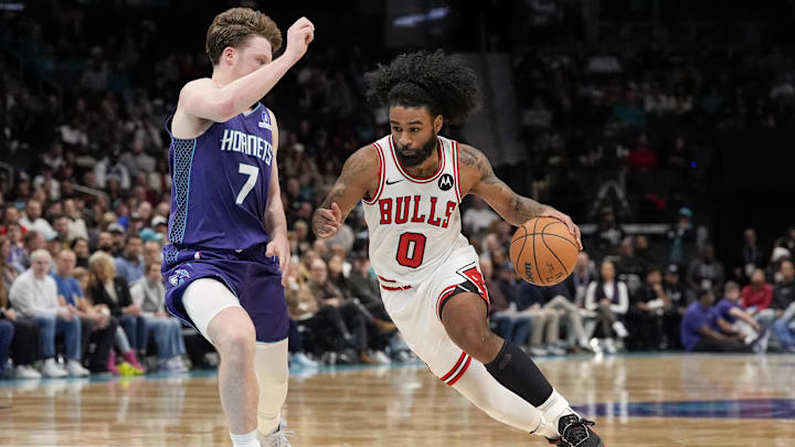 Dec 12, 2025; Charlotte, North Carolina, USA; Chicago Bulls guard Coby White (0) drives to the basket against Charlotte Hornets guard Kon Knueppel (7) during the second half at Spectrum Center. Mandatory Credit: Jim Dedmon-Imagn Images