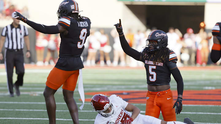 Nov 4, 2023; Stillwater, Oklahoma, USA; Oklahoma State Cowboys safety Kendal Daniels (5) and safety Trey Rucker (9) celebrate beside Oklahoma Sooners wide receiver Brenen Thompson (15) after stopping Oklahoma on a fourth down during a Bedlam college football game between the Oklahoma State University Cowboys (OSU) and the University of Oklahoma Sooners (OU) at Boone Pickens Stadium. Mandatory Credit: Bryan Terry-Imagn Images Nov 4, 2023; Stillwater, Oklahoma, USA; Oklahoma State Cowboys safety Kendal Daniels (5) and safety Trey Rucker (9) celebrate beside Oklahoma Sooners wide receiver Brenen Thompson (15) after stopping Oklahoma on a fourth down during a Bedlam college football game between the Oklahoma State University Cowboys (OSU) and the University of Oklahoma Sooners (OU) at Boone Pickens Stadium. Mandatory Credit: Bryan Terry-Imagn Images