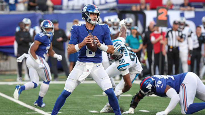Aug 18, 2023; East Rutherford, New Jersey, USA; New York Giants quarterback Daniel Jones (8) drops back top pass during the first quarter as Carolina Panthers linebacker Amare Barno (90) pursues at MetLife Stadium. Mandatory Credit: Vincent Carchietta-Imagn Images
