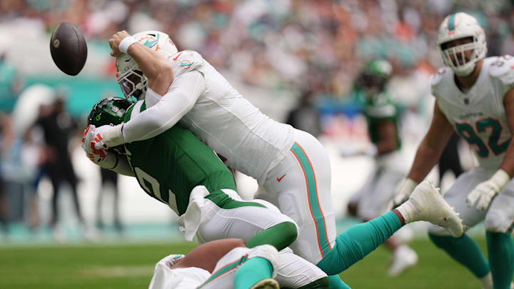 Miami Dolphins linebacker Bradley Chubb, top, and defensive tackle Christian Wilkins, bottom, hit New York Jets quarterback Zach Wilson (2) causing a fumble during the first half of an NFL game at Hard Rock Stadium in Miami Gardens, Dec. 17, 2023.