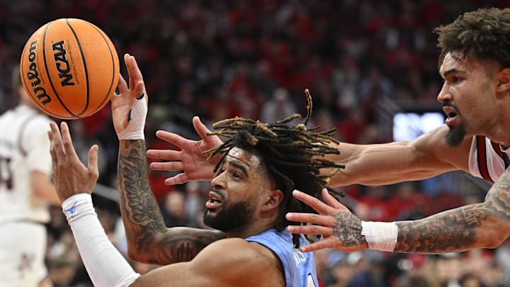 Jan 1, 2025; Louisville, Kentucky, USA;  North Carolina Tar Heels guard RJ Davis (4) looks to pass the ball while under the pressure of Louisville Cardinals guard J'Vonne Hadley (1) during the second half at KFC Yum! Center. Mandatory Credit: Jamie Rhodes-Imagn Images