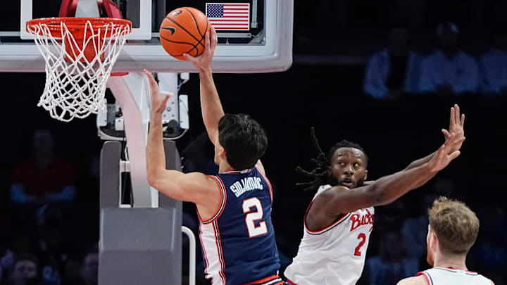 Illinois Fighting Illini guard Andrej Stojakovic (2) shoots over Ohio State Buckeyes guard Bruce Thornton (2) during the first half of the NCAA men's basketball game in Columbus on Dec. 9, 2025. Ohio State lost 86-78.