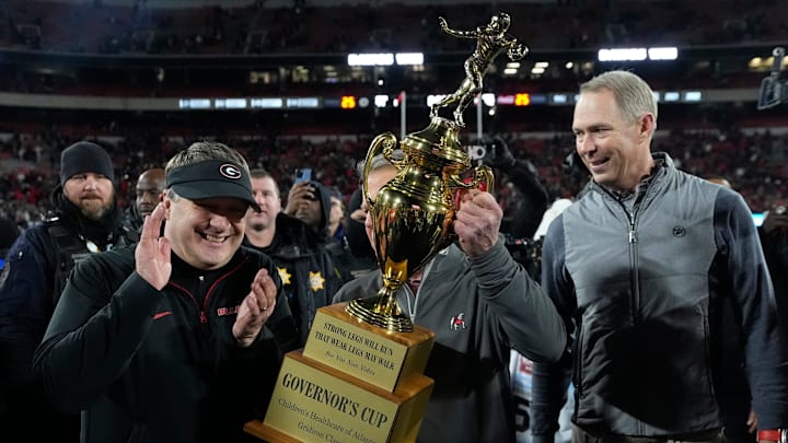 Georgia Governor Kemp hands Georgia coach Smart the governor cup after Georgia beat Georgia Tech in eight overtimes. Georgia Governor Kemp hands Georgia coach Smart the governor cup after Georgia beat Georgia Tech in eight overtimes.
