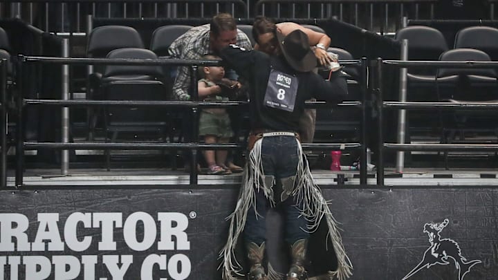 Mason Clements, of Spanish Fork, Utah, pulls himself up on the rail for a kiss after a successful bareback bronc ride at the rodeo on Thursday, May 9, 2024, in Corpus Christi, Texas.