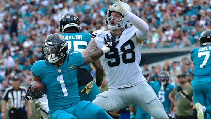 Jacksonville Jaguars running back Travis Etienne Jr. (1) pushes off on Las Vegas Raiders defensive end Maxx Crosby (98) as he tries to make a run during late first quarter action. The Jacksonville Jaguars hosted the Las Vegas Raiders at TIAA Bank Field in Jacksonville, FL Sunday November 6, 2022. The Jaguars trailed 20 to 10 at the end of the first half. [Bob Self/Florida Times-Union]

Jki 110622 Bs Jaguars Vs Raiders 53