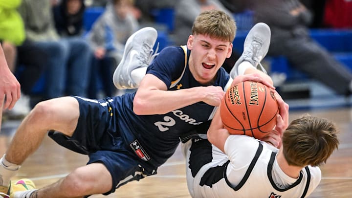 Whitnall guard Myles Herro (blue uniform) and Kaukauna guard Josh Carl wrestle for a ball on the floor in a game in the Rick Majerus WBY Shootout on Friday, December 27, 2024, at Concordia University in Mequon, Wisconsin. Whitnall won, 59-56.