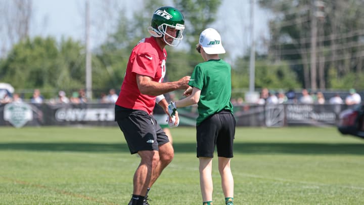 Jul 27, 2024; Florham Park, NJ, USA; New York Jets quarterback Aaron Rodgers (8) performs an elaborate handshake with a young fan during training camp at Atlantic Health Jets Training Center.