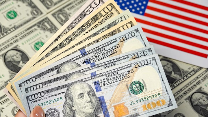 In this photo illustration, a hand holds several U.S. dollar...