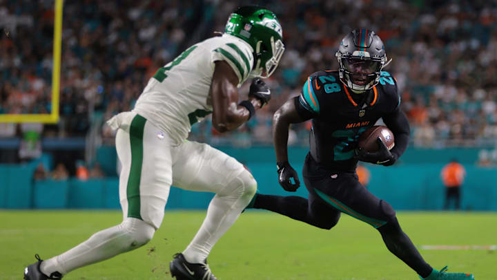 Sep 29, 2025; Miami Gardens, Florida, USA;  Miami Dolphins running back De'von Achane (28) rushes the ball against New York Jets cornerback Brandon Stephens (21) during the first half at Hard Rock Stadium. Mandatory Credit: Sam Navarro-Imagn Images