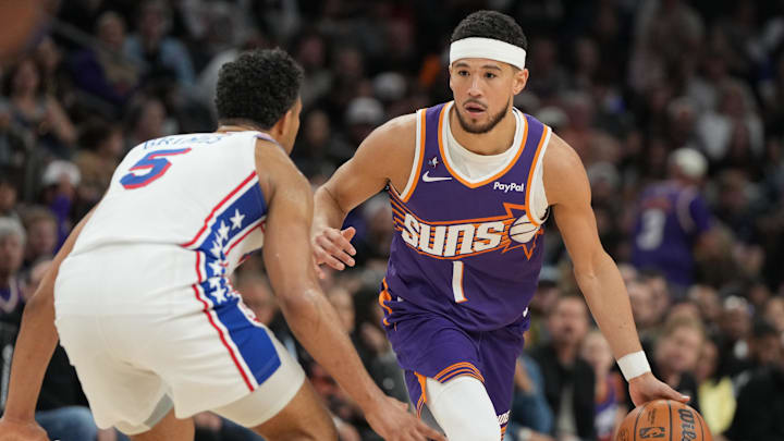 Feb 7, 2026; Phoenix, Arizona, USA; Phoenix Suns guard Devin Booker (1) drives on Philadelphia 76ers guard Quentin Grimes (5) during the first half of an NBA game at Mortgage Matchup Center. Mandatory Credit: Rick Scuteri-Imagn Images