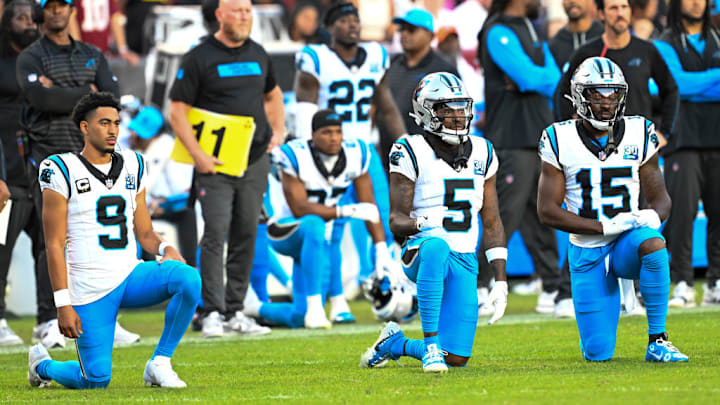 LANDOVER, MARYLAND - OCTOBER 20: Carolina Panthers players take a knee while Raheem Blackshear #3 of the Carolina Panthers is attended to by team medical staff during the third quarter against the Washington Commanders at Northwest Stadium on October 20, 2024 in Landover, Maryland.