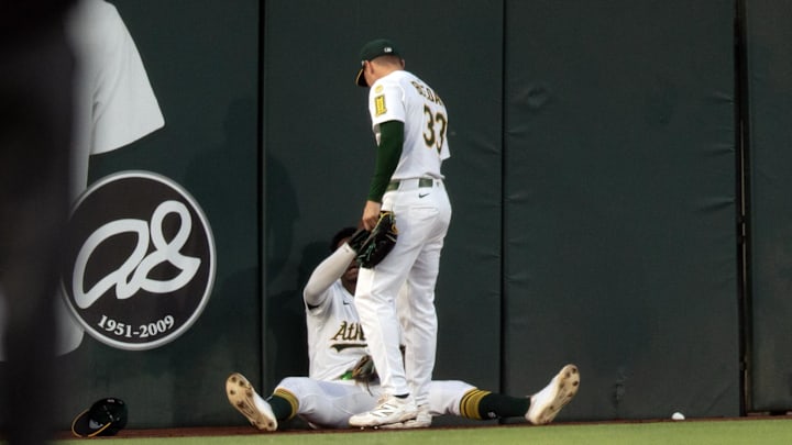 Jun 6, 2025; West Sacramento, California, USA; Athletics left fielder JJ Bleday (33) helps up center fielder Denzel Clarke (1) after he collided with the wall tracking down a deep fly ball by Baltimore Orioles shortstop Jorge Mateo during the fourth inning at Sutter Health Park. Mandatory Credit: D. Ross Cameron-Imagn Images