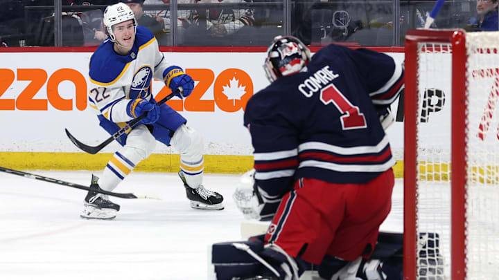 Mar 23, 2025; Winnipeg, Manitoba, CAN; Buffalo Sabres right wing Jack Quinn (22) takes a shot on Winnipeg Jets goaltender Eric Comrie (1) in the first period at Canada Life Centre. Mandatory Credit: James Carey Lauder-Imagn Images