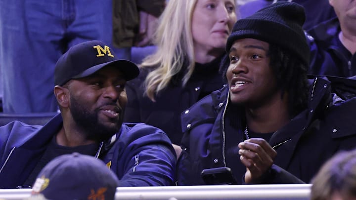 Dec 7, 2024; Ann Arbor, Michigan, USA;  Michigan Wolverines head coach football Sherrone Moore and quarterback commit Bryce Underwood talk in the first half of a basketball game against the Iowa Hawkeyes at Crisler Center. Mandatory Credit: Rick Osentoski-Imagn Images
