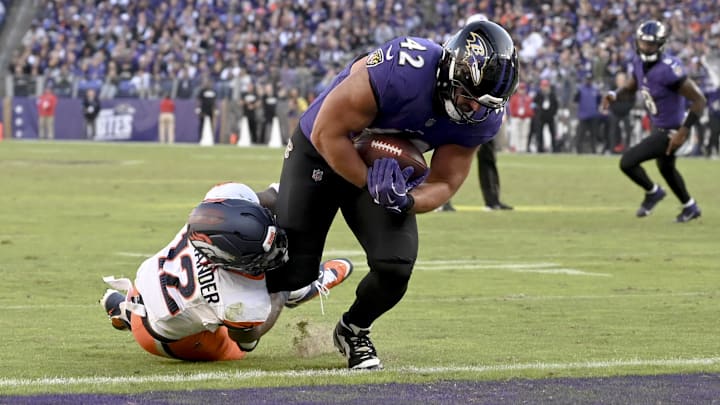 Nov 3, 2024; Baltimore, Maryland, USA;  Baltimore Ravens fullback Patrick Ricard (42) dives through Denver Broncos linebacker Kwon Alexander (12) tackle attempt for a touchdown  during the second half at M&T Bank Stadium. Mandatory Credit: Tommy Gilligan-Imagn Images