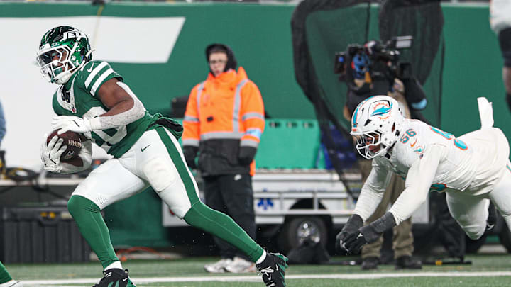 Jan 5, 2025; East Rutherford, New Jersey, USA; New York Jets running back Breece Hall (20) breaks a tackle by Miami Dolphins linebacker Quinton Bell (56) for a touchdown reception during the second half at MetLife Stadium. Mandatory Credit: Vincent Carchietta-Imagn Images Jan 5, 2025; East Rutherford, New Jersey, USA; New York Jets running back Breece Hall (20) breaks a tackle by Miami Dolphins linebacker Quinton Bell (56) for a touchdown reception during the second half at MetLife Stadium. Mandatory Credit: Vincent Carchietta-Imagn Images