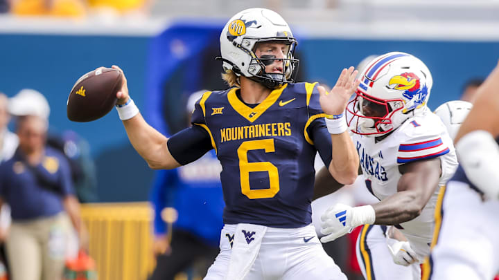 Sep 21, 2024; Morgantown, West Virginia, USA; West Virginia Mountaineers quarterback Garrett Greene (6) throws a pass and is rushed by Kansas Jayhawks linebacker JB Brown (1) during the first quarter at Mountaineer Field at Milan Puskar Stadium. Mandatory Credit: Ben Queen-Imagn Images