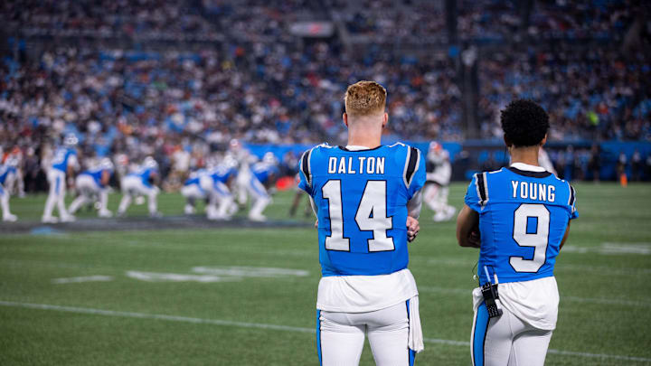 Aug 8, 2025; Charlotte, North Carolina, USA; Carolina Panthers quarterback Andy Dalton (14) and quarterback Bryce Young (9) watch from the sidelines during the fourth quarter at Bank of America Stadium. 