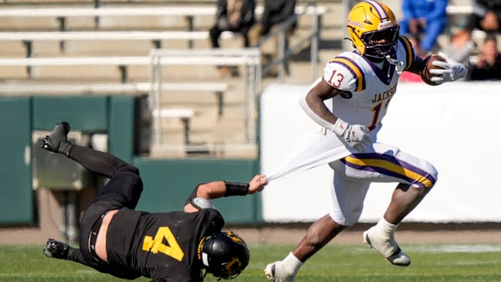 Dec 6, 2024; Birmingham, AL, USA; Cherokee County's Tristan Brown (4) tries to hang on for a tackle as Jackson's Ezavier Crowell (13) pulls away at Protective Stadium in the AHSAA 4A State Championship game.