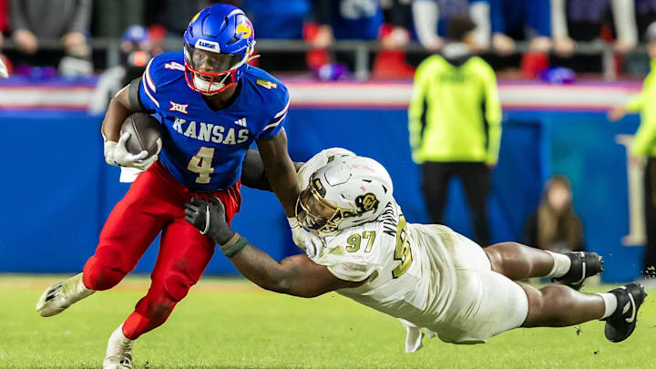 Nov 23, 2024; Kansas City, Missouri, USA;  Kansas running back Devin Neal (4) maneuvers past a diving during the Colorado defensive tackle Chidozie Nwankwo (97) in the 4th quarter between the Kansas Jayhawks and the Colorado Buffaloes at GEHA Field at Arrowhead Stadium. Mandatory Credit: Nick Tre. Smith-Imagn Images