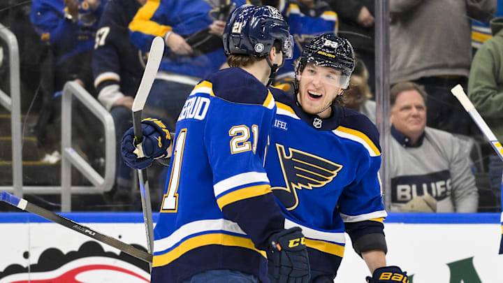 Apr 3, 2025; St. Louis, Missouri, USA;  St. Louis Blues right wing Jimmy Snuggerud (21) celebrates after assisting on a goal by left wing Jake Neighbours (63) for his first NHL point during the third period against the Pittsburgh Penguins at Enterprise Center. Mandatory Credit: Jeff Curry-Imagn Images