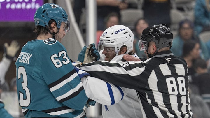 Apr 2, 2026; San Jose, California, USA;  linesman Tyson Baker (88) separates Toronto Maple Leafs center Calle Jarnkrok (19) and San Jose Sharks center Zack Ostapchuk (63) during the end of the first period at SAP Center at San Jose. Mandatory Credit: Stan Szeto-Imagn Images