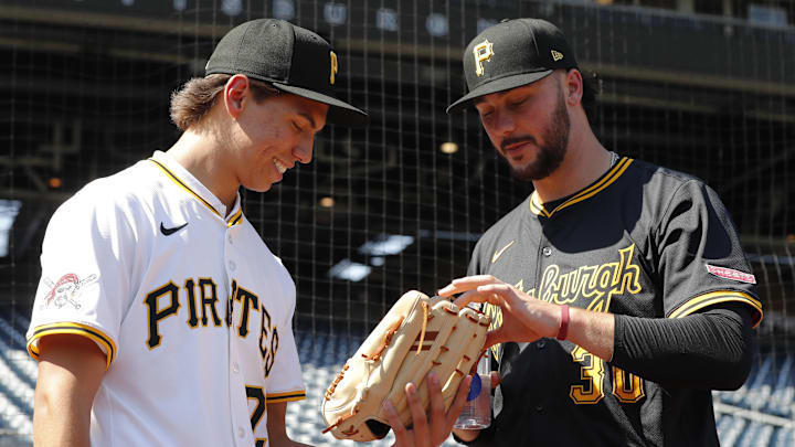 Jul 22, 2025; Pittsburgh, Pennsylvania, USA;  Seth Hernandez (left) the Pittsburgh Pirates first round and number six overall pick in the 2025 first year player draft looks at the glove of Pirates pitcher Paul Skenes (30) before the game against the Detroit Tigers at PNC Park. Mandatory Credit: Charles LeClaire-Imagn Images